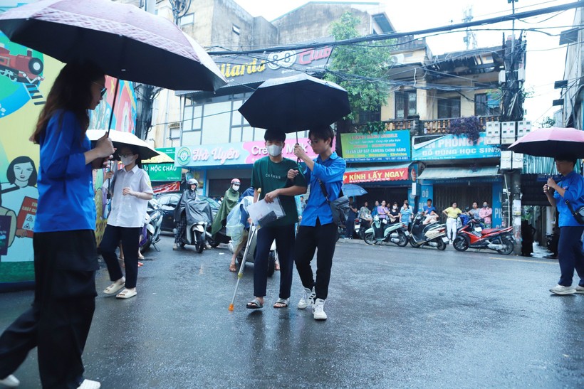 Một thí sinh bị đau chân phải chống nạng được đoàn viên thanh niên hỗ trợ từ cổng.