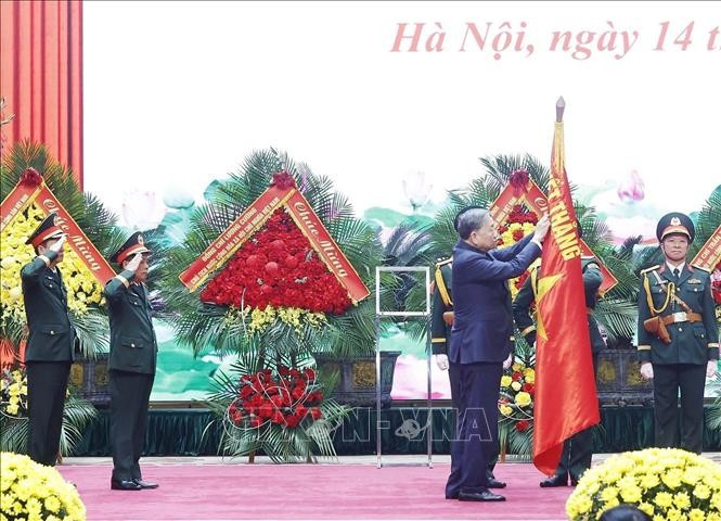 Tổng Bí thư Tô Lâm gắn Danh hiệu Anh hùng lực lượng vũ trang nhân dân lên Quân kỳ Quyết thắng của Tổng cục Hậu cần - Kỹ thuật. Ảnh: Thống Nhất/TTXVN