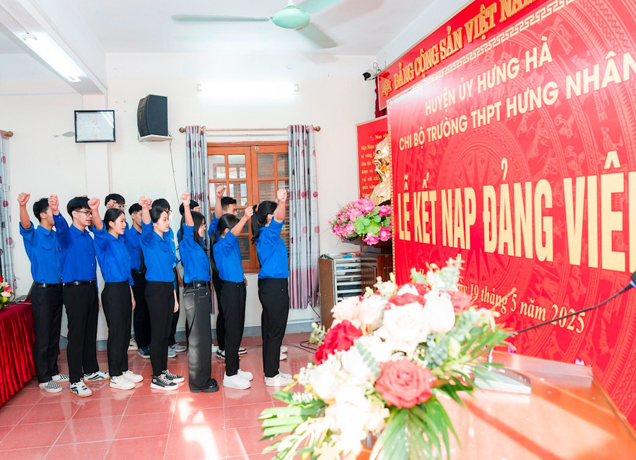 Đảng viên trẻ Trường THPT Hưng Nhân tuyên thệ trước cờ Đảng, cờ Tổ quốc và chân dung Chủ tịch Hồ Chí Minh.